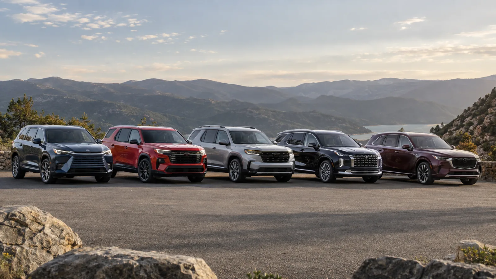 Five modern three-row SUVs parked at a mountain overlook